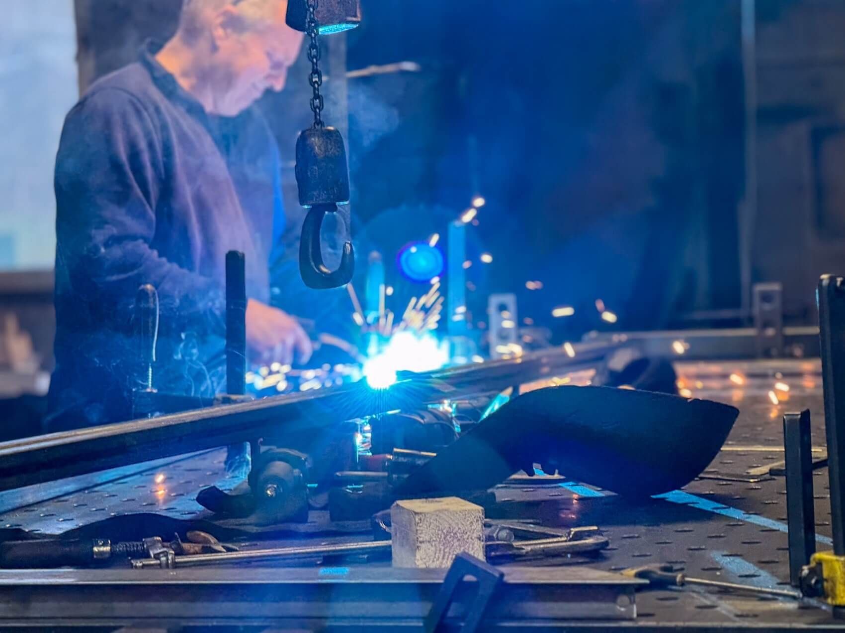 Mann schweisst an einem Stück Metall 