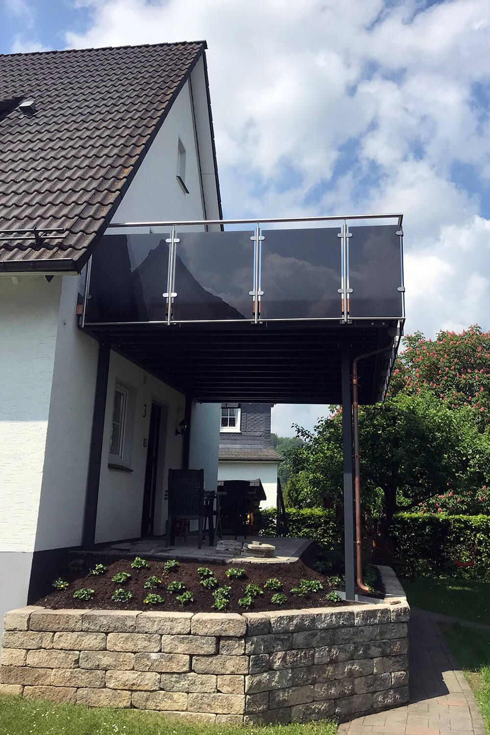 Vorgesetzte Terrasse mit Absturzsicherung aus dunklem Glas